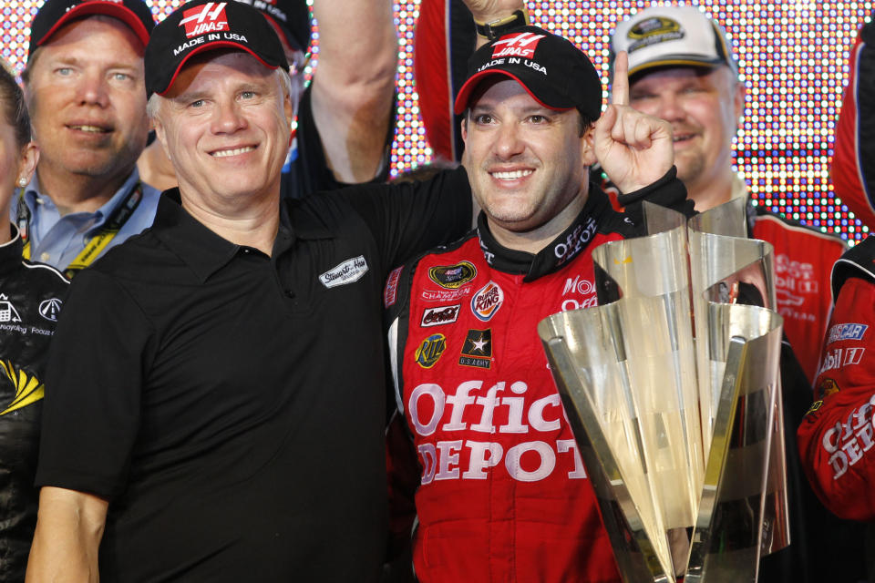 FILE - Team co-owner Carl Haas and Tony Stewart, right, pose with the NASCAR Sprint Cup Series season-championship trophy at Homestead-Miami Speedway in Homestead, Fla., Sunday, Nov. 20, 2011. Stewart-Haas Racing will close its NASCAR team at the end of the 2024 season, co-team owners Tony Stewart and Gene Haas said in a joint statement Tuesday, May 28, 2024. (AP Photo/Terry Renna, File)