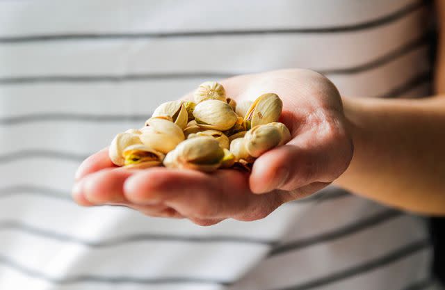 <p>Kinga Krzeminska / Getty Images</p> A handful of pistachios