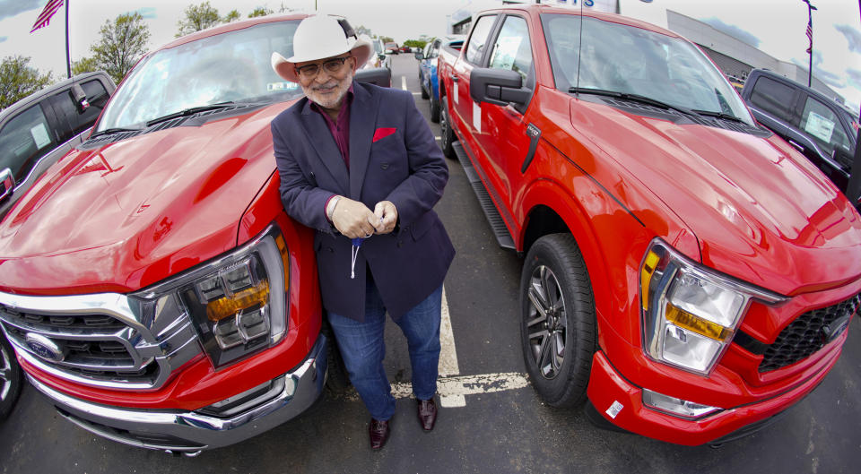 In this photo made on Thursday, May 6, 2021, Shults Ford dealership owner Richard Bazzy stands between two of the remaining Ford F150 pickups on the front line on their dealership lot in Wexford, Pa. Ford is warning that it expects to make only half the normal number of vehicles from now through June. Bazzy normally stocks 400-500 pickup trucks at his three Ford dealers, but is down around 100. He's confident that he can keep customers happy if they can order a truck and get it in four weeks, but he fears losing business to competing brands with a huge stock. (AP Photo/Keith Srakocic)