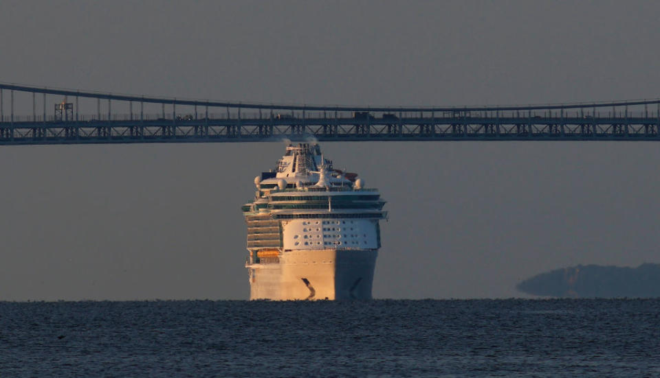 A cruise ship appears to be almost the same size as a distant bridge above it