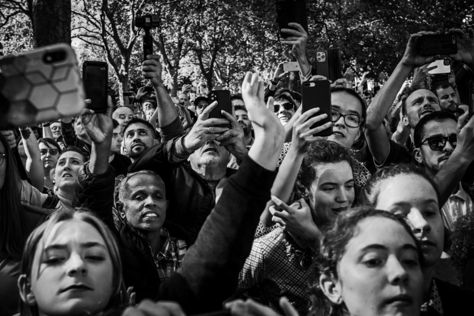 Members of the public use their mobile phones to make a picture and catch glimpse of the procession