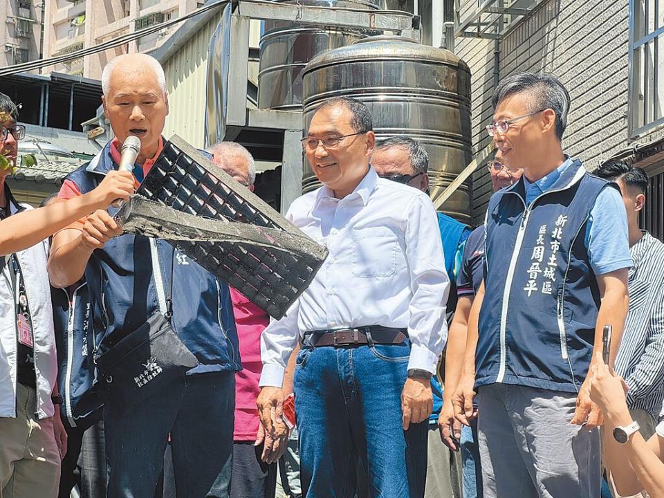 新北市長侯友宜（前排中）在土城區埤林里長蔡志紅（前排左）帶領下視察登革熱防疫工作，蔡志紅向侯友宜示範環保志工與里長平日如何維護環境整潔、防止下水道孳生孑孓。（柯毓庭攝）