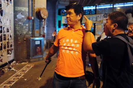 A man gestures at a pro-China supporter as they clean up “Lennon Walls” of anti-government posters and memo notes outside Yuen Long MTR station in Hong Kong