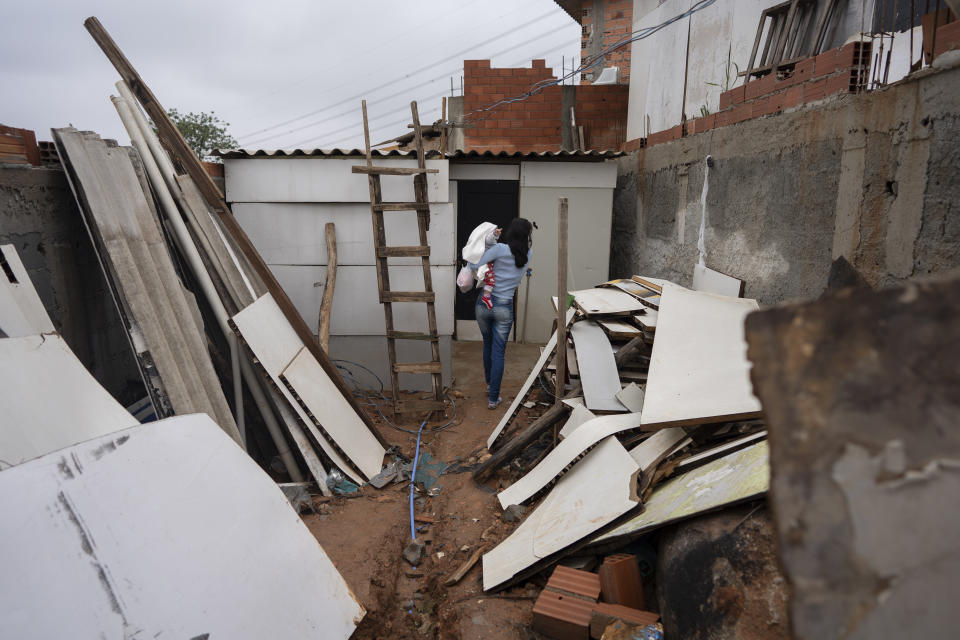 Erika Correia dos Santos, 23, walks into her one-room shack holding her 7-month-old daughter Sara in Brasiliandia, one of Sao Paulo's poorest neighborhoods, in Brazil, Thursday, Sept. 29, 2022. Although this year the economy started recovering, rampant inflation put even basic foodstuffs out of people's reach and thirty-three million Brazilians experience hunger as they head into the Oct. 2nd general elections. (AP Photo/Victor R. Caivano)