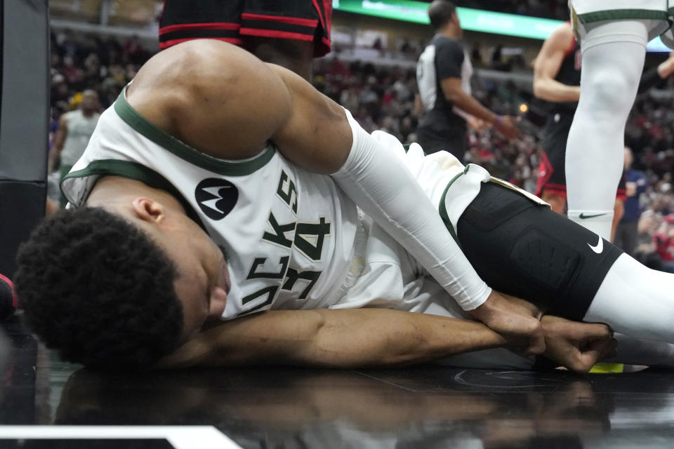 Milwaukee Bucks' Giannis Antetokounmpo lies by the basket after injuring his right wrist during the first half of the team's NBA basketball game against the Chicago Bulls on Thursday, Feb. 16, 2023, in Chicago. (AP Photo/Charles Rex Arbogast)