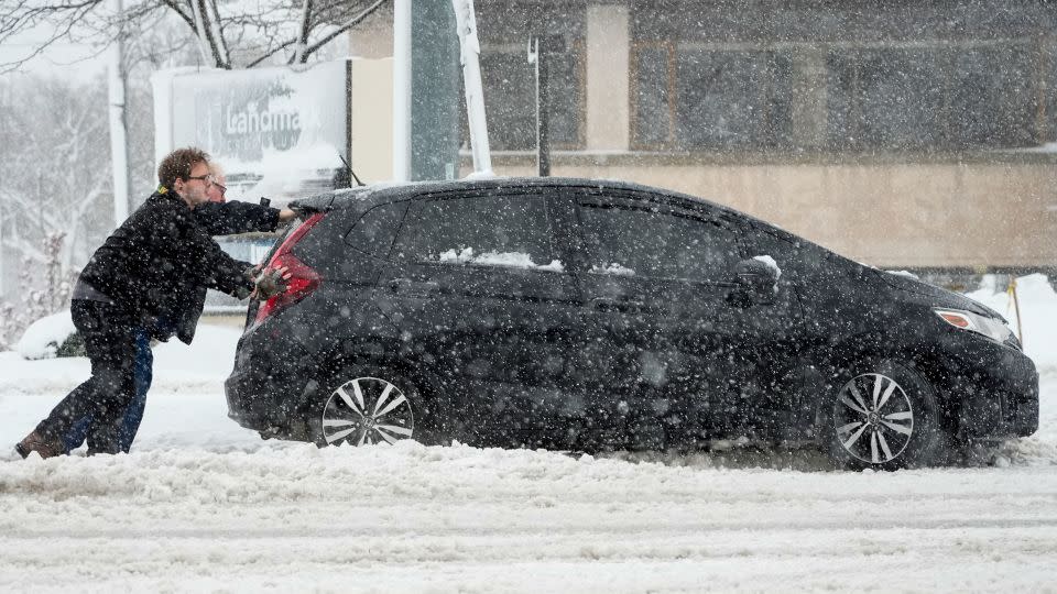 People push a car out of a snowbank as a winter storm arrives Friday, Jan. 12, 2024, in West Allis, Wisconsin. - Morry Gash/AP