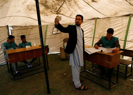 Afghan man takes a selfie as he arrives at a voter registration centre to register for the upcoming parliamentary and district council elections in Kabul, Afghanistan April 23, 2018. REUTERS/Mohammad Ismail