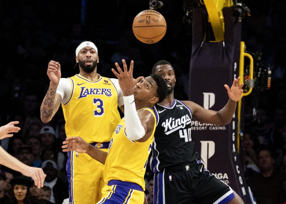 The Lakers' Rui Hachimura reaches out for a rebound in front of the Kings' Harrison Barnes and Laker Anthony Davis