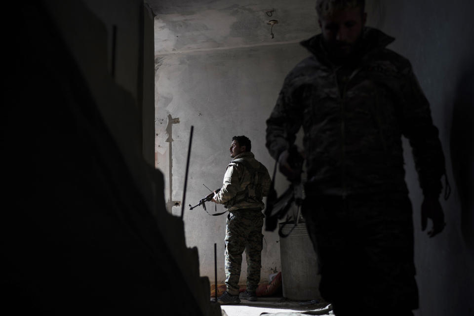 U.S.-backed Syrian Democratic Forces (SDF) fighters walk in a building as fight against Islamic State militants continue in the village of Baghouz, Syria, Saturday, Feb. 16, 2019. (AP Photo/Felipe Dana)