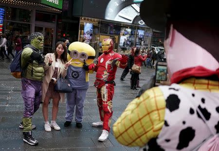 A tourist (2nd L) poses with two people dressed as Hulk and Iron Man, as another dressed as Woody from Toy Story takes their photo in Times Square, in New York, April 7, 2016. REUTERS/Rickey Rogers