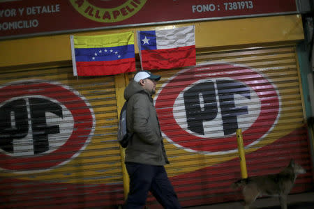 Venezuelan immigrant, Rafael Castillo, walks past flags of Venezuela and Chile at La Vega market in Santiago, Chile, May 10, 2018. Castillo is a lawyer who has live along one year in Chile, nowadays he works as a store clerk in Santiago. REUTERS/Ivan Alvarado