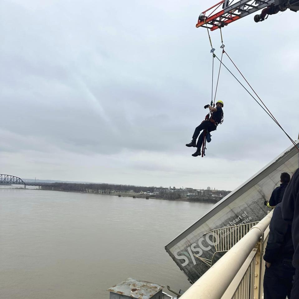 This photo provided by Louisville Division of Fire, Louisville Fire Dept., Louisville firefighter Bryce Carden rescues the driver of semitruck that is dangling off the Clark Memorial Bridge over the Ohio River on Friday, March 1, 2024 in Louisville, Ky. The driver was pulled to safety by firefighters following the three-vehicle crash on the bridge connecting Louisville, Kentucky to southern Indiana. (Louisville Division of Fire via AP)