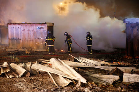 Firefighters extinguish shelters during a fire which destroyed many wood houses at a camp for migrants in Grande-Synthe, near Dunkirk, France, April 11, 2017. REUTERS/Pascal Rossignol