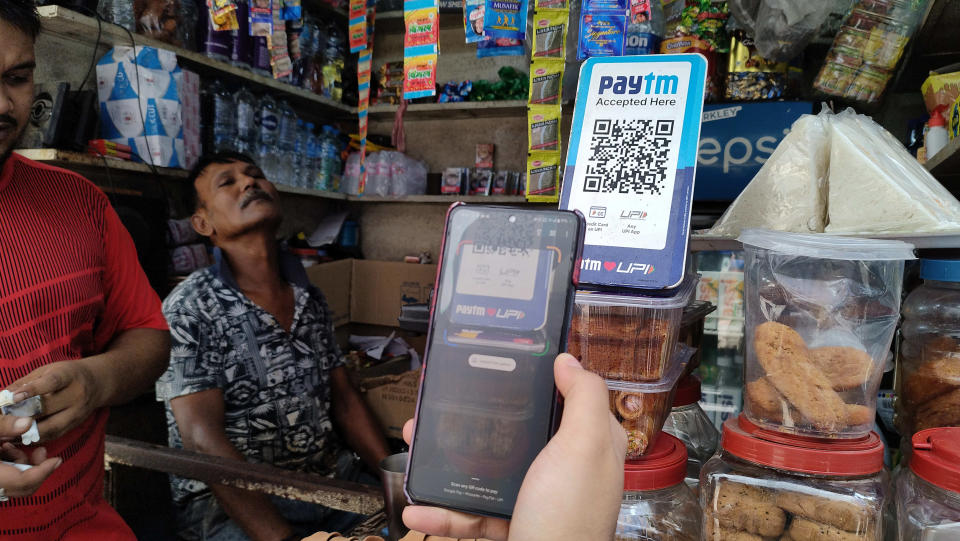 A man is using his phone to scan a QR code of the digital payment app Paytm after purchasing some food at a shop in Kolkata, India