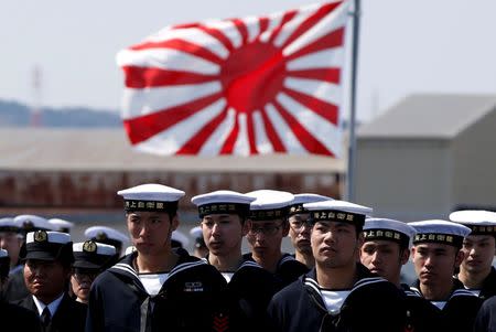 FILE PHOTO:Crew members of the Japan Maritime Self-Defense Force's (JMSDF) latest Izumo-class helicopter carrier DDH-184 Kaga are seen in front of Japan's naval flag during a handover ceremony for the JMSDF by Japan Marine United Corporation in Yokohama, Japan, March 22, 2017. REUTERS/Toru Hanai/File Photo