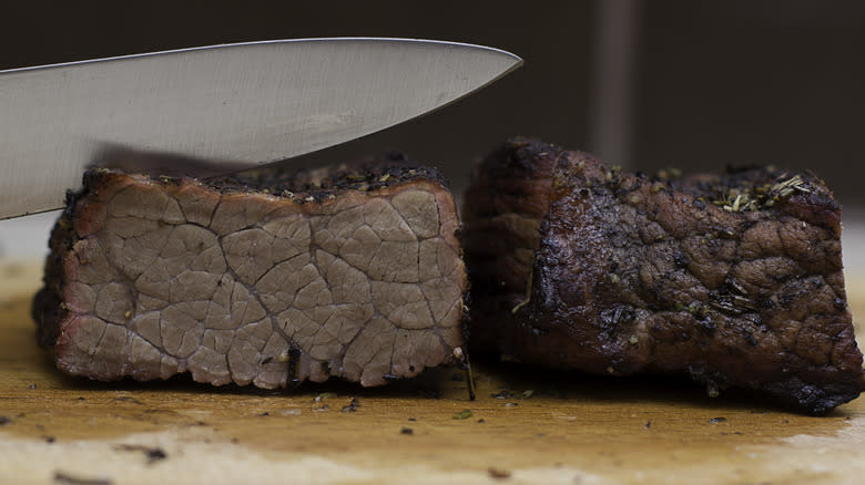 knife cutting into overcooked steak