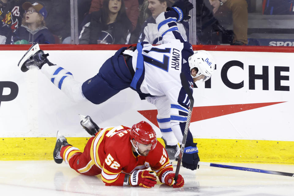 Winnipeg Jets' Adam Lowry (17) runs into Calgary Flames' MacKenzie Weegar during the first period of an NHL hockey game in Calgary, Alberta, Monday, Feb. 19, 2024. (Larry MacDougal/The Canadian Press via AP)