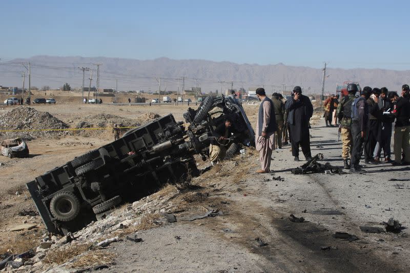 Police officers in civilian clothes survey the aftermath of a suicide bomb blast on a police patrol in Quetta