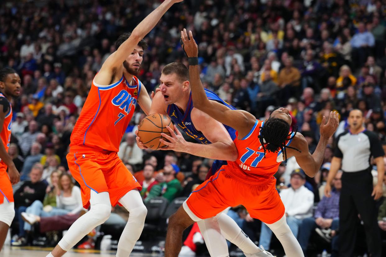 Dec 16, 2023; Denver, Colorado, USA; Denver Nuggets center Nikola Jokic (15) drives against Oklahoma City Thunder guard Isaiah Joe (11) and forward Chet Holmgren (7) in the second half at Ball Arena. Mandatory Credit: Ron Chenoy-USA TODAY Sports