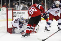 Columbus Blue Jackets goaltender Elvis Merzlikins (90) makes a save on a shot with New Jersey Devils center Jack Hughes (86) in front of him and Blue Jackets center Boone Jenner (38) watching during the second period of an NHL hockey game, Sunday, Feb. 16, 2020, in Newark, N.J. (AP Photo/Kathy Willens)