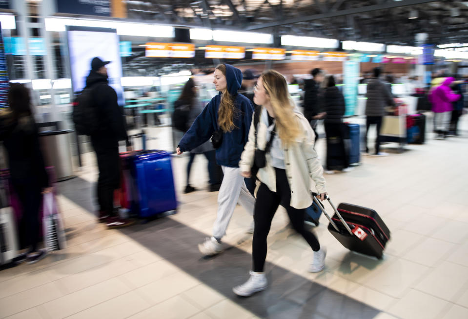 Travelers pass lineups at the Ottawa International Airport, as airlines cancel or delay flights during a major storm in Ottawa, on Friday, Dec. 23, 2022. (Justin Tang /The Canadian Press via AP)