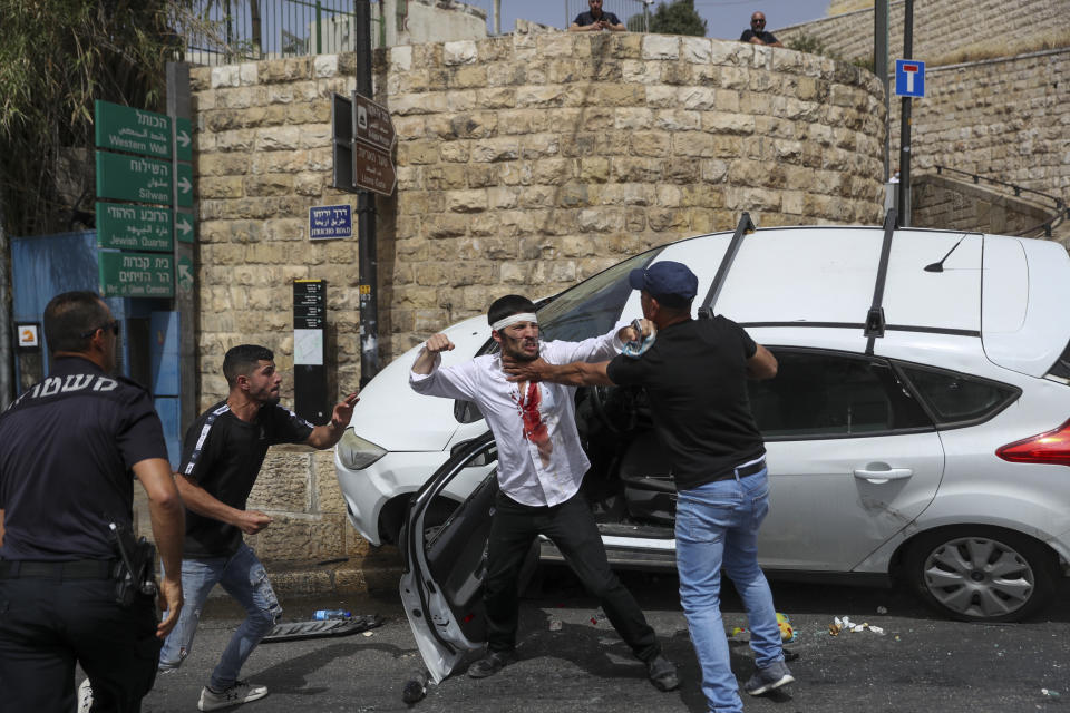 A Jewish driver, center, scuffles with Palestinians after he was attacked by Palestinian protesters near Jerusalem's Old City. Monday, May 10, 2021. Israeli police clashed with Palestinian protesters at a flashpoint Jerusalem holy site on Monday, the latest in a series of confrontations that is pushing the contested city to the brink of eruption. Palestinian medics said at least 200 Palestinians were hurt in the violence at the Al-Aqsa Mosque compound, including 150 who were hospitalized. (AP Photo/Ohad Zwigenberg)