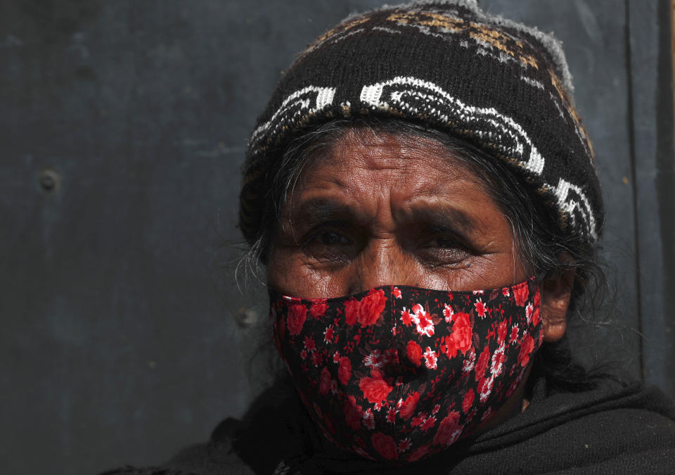 A woman wearing a protective face mask speaks with healthcare workers during a house-to-house campaign to help curb the spread of the new coronavirus, in the Mallasa neighborhood of La Paz, Bolivia, Saturday, Aug. 8, 2020. (AP Photo/Juan Karita)