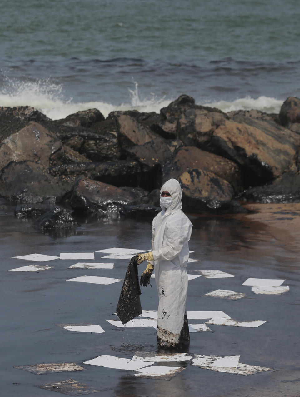 A Sri Lankan coast guard person in protective clothes works to remove oil from a beach following an oil spill in Uswetakeiyawa, a coastal town north of Colombo, Sri Lanka, Monday, Sept. 10, 2019.Sri Lanka deployed hundreds of coast guard and navy personnel on Monday to clean oil slicks on a coastal stretch near the capital following a spill caused by a pipeline leak. (AP Photo/Eranga Jayawardena)