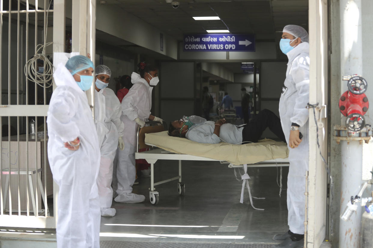 FILE - In this April 15, 2021, file photo, health workers carry a patient into a dedicated COVID-19 hospital in Ahmedabad, India. The picture is still grim in parts of Europe and Asia as variants of the virus fuel an increase in new cases and the worldwide death toll closes in on 3 million. (AP Photo/Ajit Solanki, File)