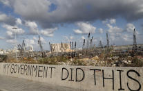 FILE - In this Aug. 9, 2020 file photo, political graffiti is visible in front of the scene of the Aug. 4 explosion that hit the seaport of Beirut, Lebanon. On Thursday, Oct. 22, 2020, Human Rights Watch said a Lebanon-led probe into the devastating explosion has been marred by political meddling and lack of judicial independence, resulting in the failure to yield credible results two months later. HRW called for a United Nations-led inquiry into the blast. (AP Photo/Hussein Malla, File)