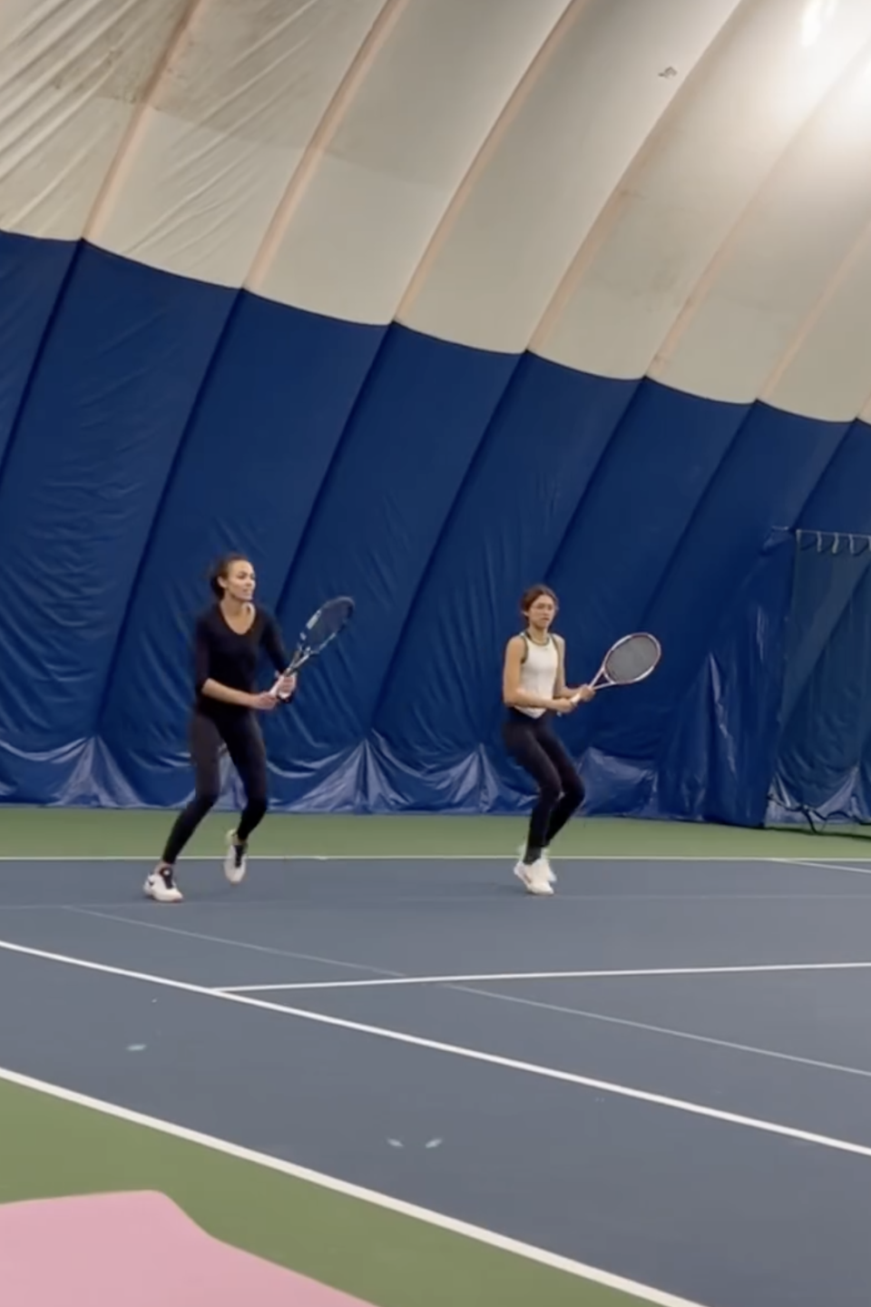 Two people playing tennis indoors