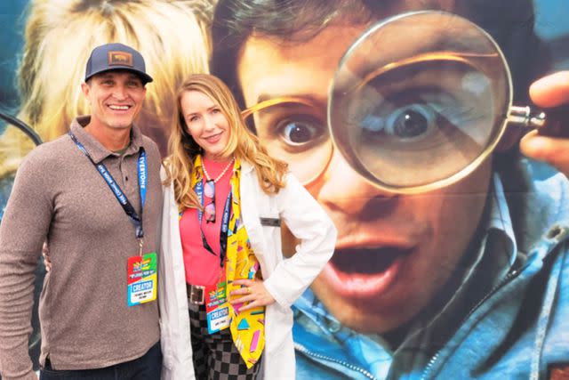 <p>Courtesy Amy O'Neill</p> Thomas Wilson Brown and Amy O'Neill pose in front of <em>Honey, I Shrunk the Kids</em> movie art featuring Rick Moranis and the late Marcia Strassman