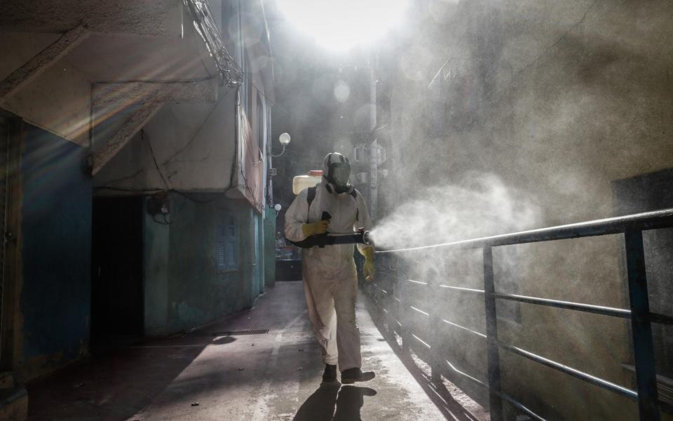 A worker wearing personal protective equipment performs disinfection operations at Dona Marta favela. Staggering under its worst period of the pandemic, with daily records of caseloads and deaths, Brazil is facing a daunting development: a rising number of deaths among the young - Andre Coelho/Bloomberg