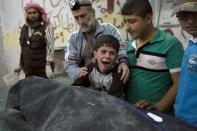 A Syrian boy cries next to the body of a relative killed in an air strike in Aleppo in April 2016