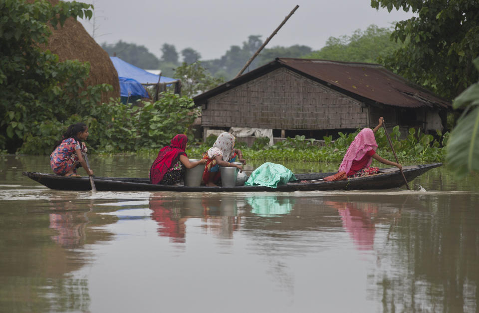 Indian flood affected women transport drinking water on a boat in Burha Burhi village, east of Gauhati, Assam, India, Monday, July 15, 2019. After causing flooding and landslides in Nepal, three rivers are overflowing in northeastern India and submerging parts of the region, affecting the lives of more than 2 million, officials said Monday. (AP Photo/Anupam Nath)