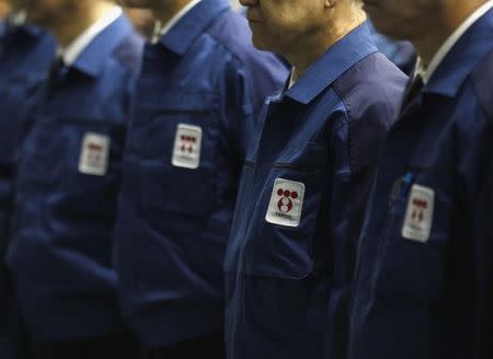 Logos of Tokyo Electric Power Co. (TEPCO), the operator of the tsunami-crippled Fukushima Daiichi nuclear plant, are seen on company uniforms as employees listen to a video speech by company president Naomi Hirose after taking part in a moment of silence at 2:46 p.m. local time (0546 GMT) at TEPCO's headquarters in Tokyo March 11, 2015, to mark the fourth anniversary of the March 11, 2011 earthquake and tsunami that killed thousands. REUTERS/Yuya Shino