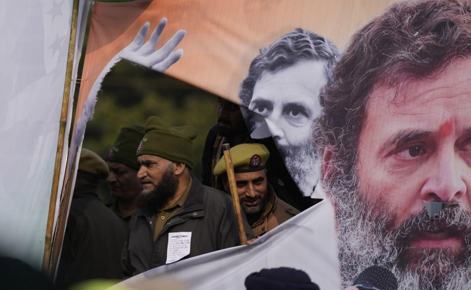 Policemen are seen through a ripped banner as India's opposition Congress party leader Rahul Gandhi, speaks