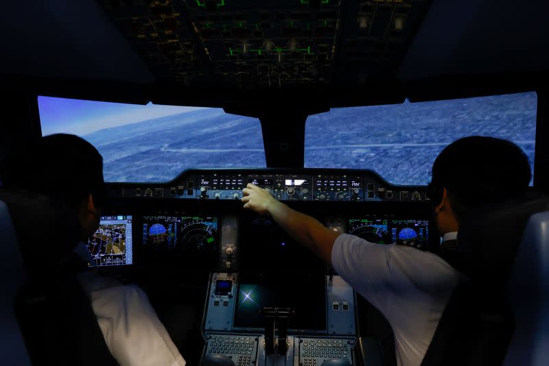 Two Starlux pilots operate a flight simulator at their center in Taoyuan