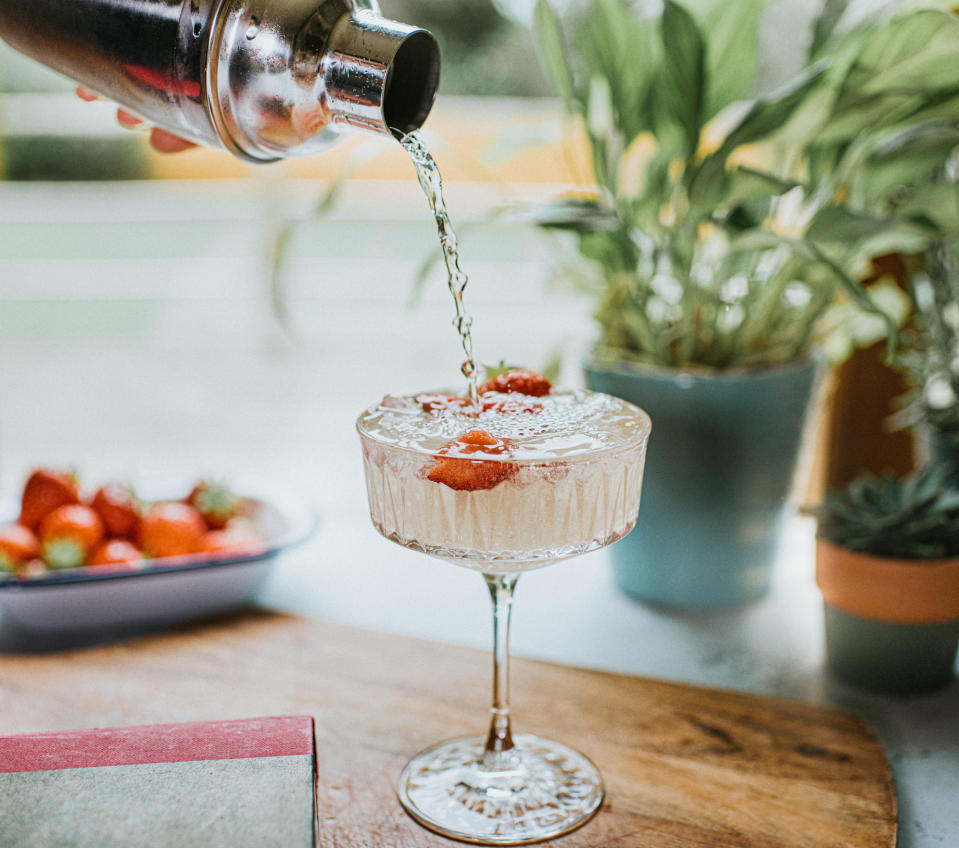 Cocktail being poured from a metal cocktail shaker into a stylish glass.