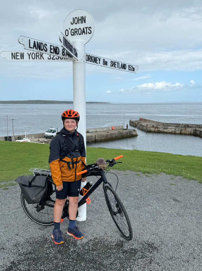 Harry Peksa poses at the sign at John O'Groats in Scotland