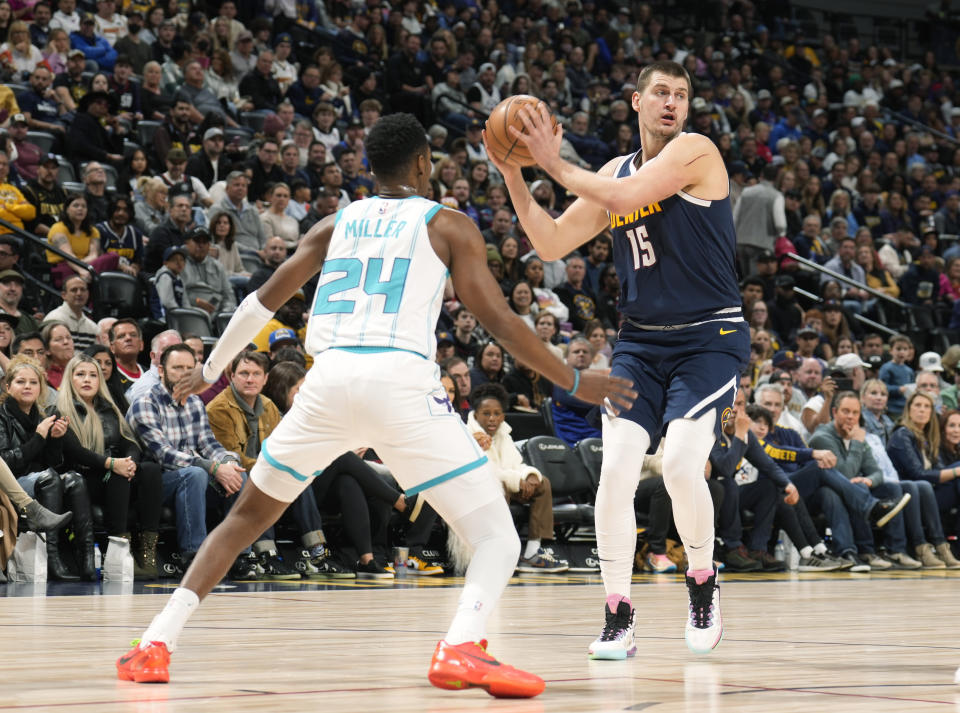 Denver Nuggets center Nikola Jokic, right, looks to pass the ball as Charlotte Hornets forward Brandon Miller defends in the first half of an NBA basketball game, Monday, Jan. 1, 2024, in Denver. (AP Photo/David Zalubowski)