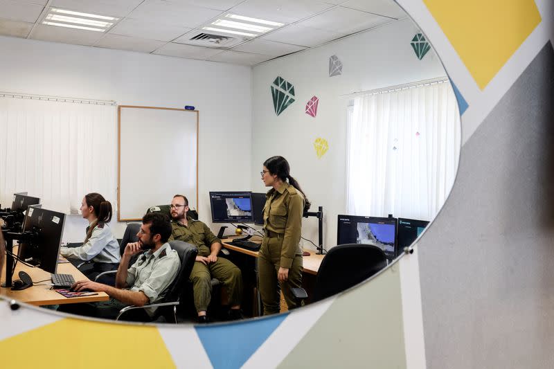 Technologists with the Israeli military's Matzpen operational data and applications unit confer at their stations at an IDF base in Ramat Gan