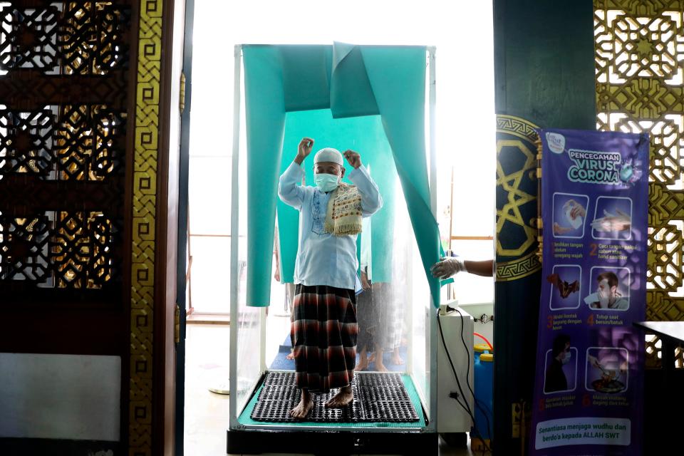 A Muslim worshipper walks through a sterilization chamber installed at the entrance of Al Akbar Mosque amid fears of the new coronavirus outbreak, prior to the start of a Friday prayer in Surabaya, on March 27.