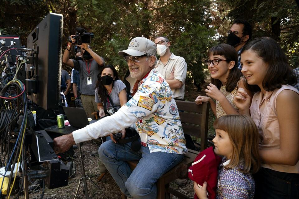 Steven Spielberg on the set of "The Fabelmans" with children looking over his shoulder.