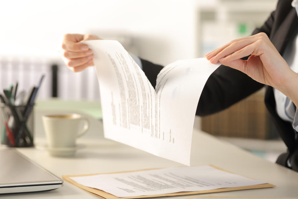 Close up of business woman hands breaking contract document sitting on a desk at the office.