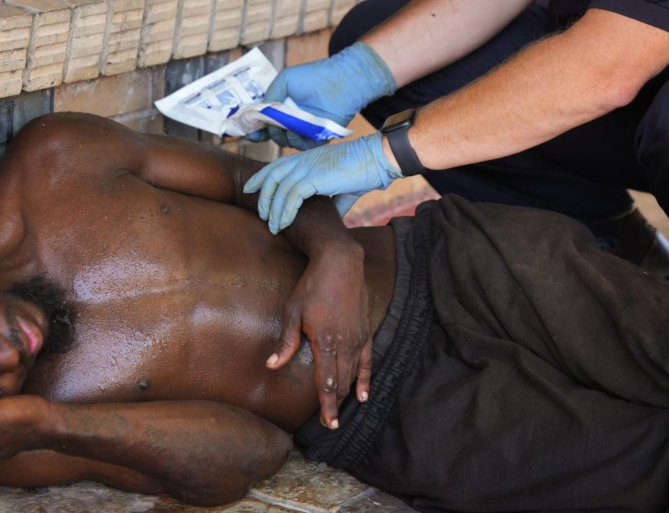 Capt. Darren Noak, an Austin-Travis County Emergency Medical Services medic, applies a chemical ice pack to a man on East Sixth Street on July 12. The temperature that day reached 107 degrees, and Austin was under an excessive heat advisory.