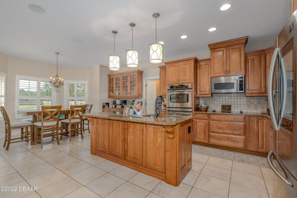 This spacious gourmet eat-in kitchen boasts an abundance of wood cabinetry, stainless-steel appliances and a center island.