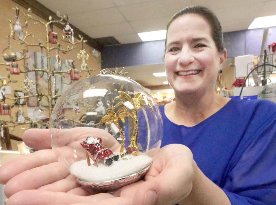 Sherry Graffagnino, owner of Molto Bella Boutique in Ormond Beach, displays a Michael Aram Island Santa Christmas ornament at her shop, which has been busy serving holiday shoppers since mid-October. "This year, people are buying early," she said. "I'm actually getting nervous because I've run out of a few things."