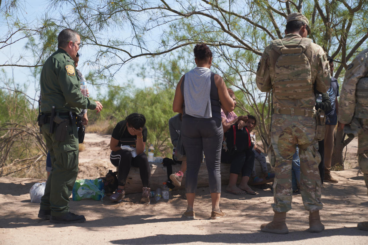 Migrants and U.S. Border Patrol agents try to help a woman after she gets sick as migrants wait during hot weather to be processed by U.S. Border Patrol after illegally crossing into Eagle Pass, Texas U.S. from Mexico on Tuesday July 26, 2022. / Credit: Allison Dinner/Anadolu Agency via Getty Images