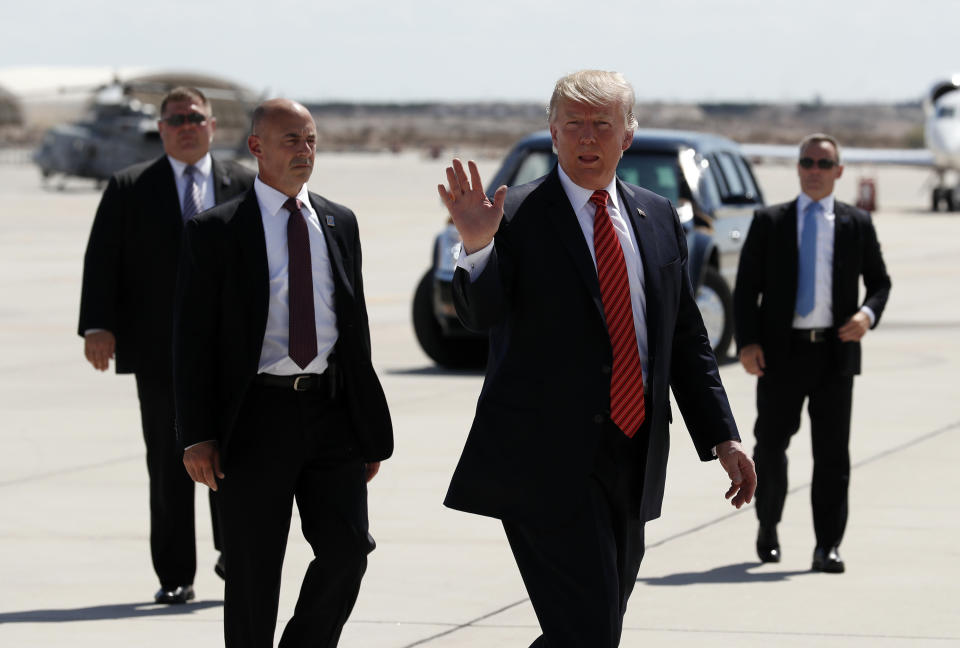 US-Präsident Donald Trump wird von drei Beschützern zur Air Force One geleitet. (Bild: AP Photos)